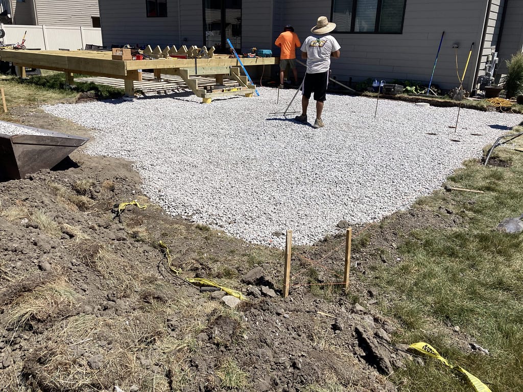 1. A man prepares a backyard patio with gravel, getting the site ready for artificial turf installation.